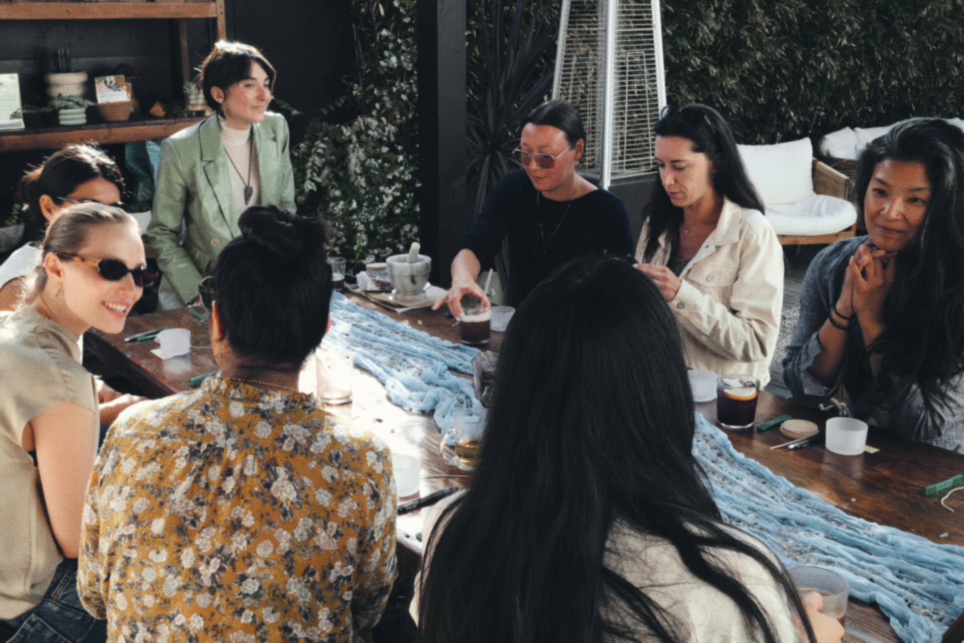 Women gathered around a long table outdoors in warm afternoon light